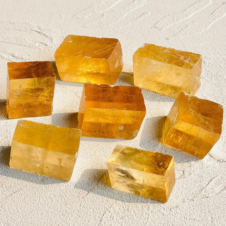 Seven raw Honey Calcite crystal clusters, radiating a rich amber glow for confidence and clarity.
