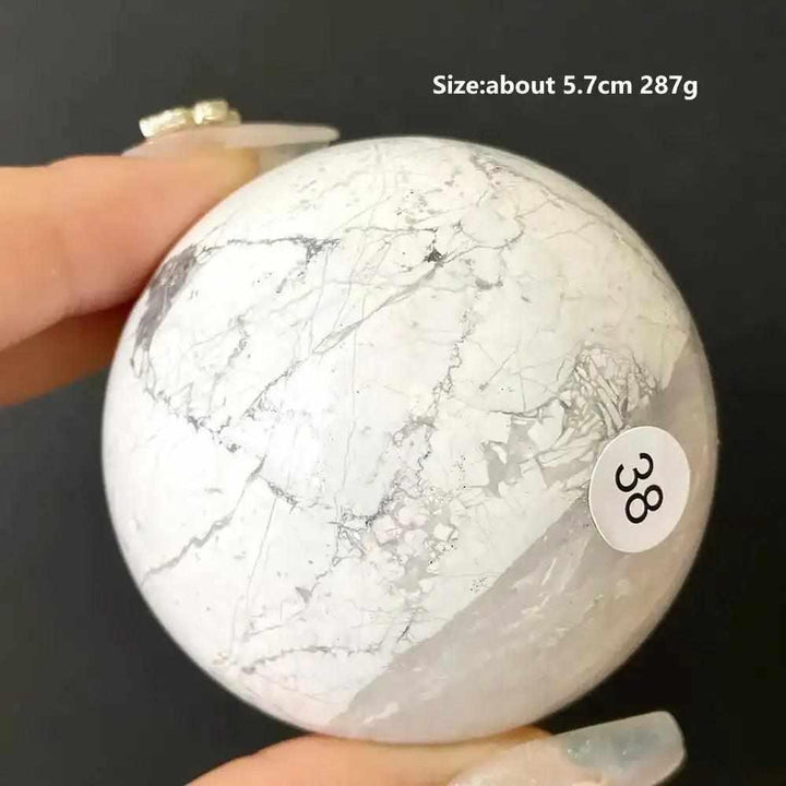 Polished 5.7cm Howlite sphere, style 38, featuring creamy white stone with delicate gray veining for calming energy.
