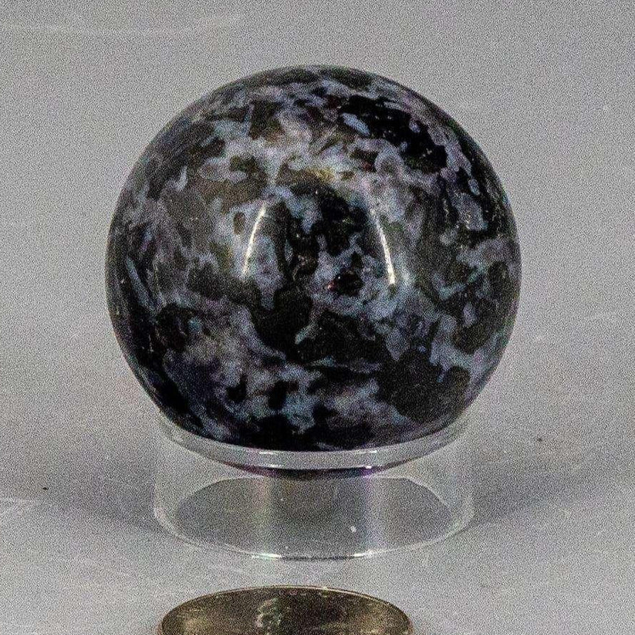 Indigo Gabbro Sphere 40mm, a polished blue-black crystal with white and indigo inclusions, showcasing its galaxy-like surface.
