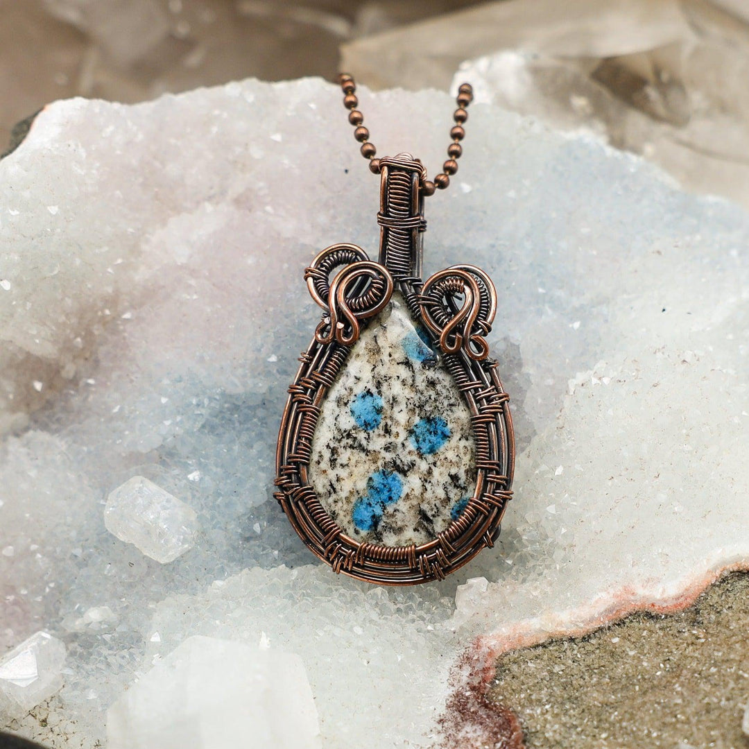 K2 Jasper Wire Wrap Pendant: Handcrafted copper wire embraces rare white granite with vivid blue Azurite orbs.