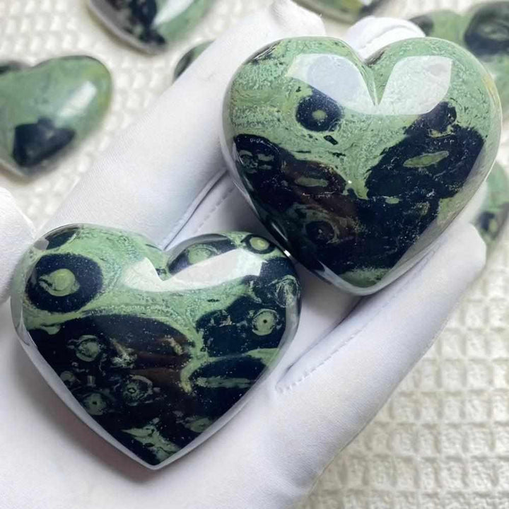 Polished Kambaba Jasper heart featuring deep green and black orb patterns for grounding and Heart Chakra healing.