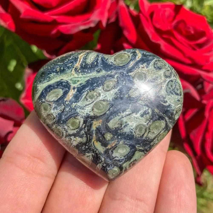 Polished Kambaba Jasper heart featuring deep green and black orb patterns for grounding and heart chakra healing.