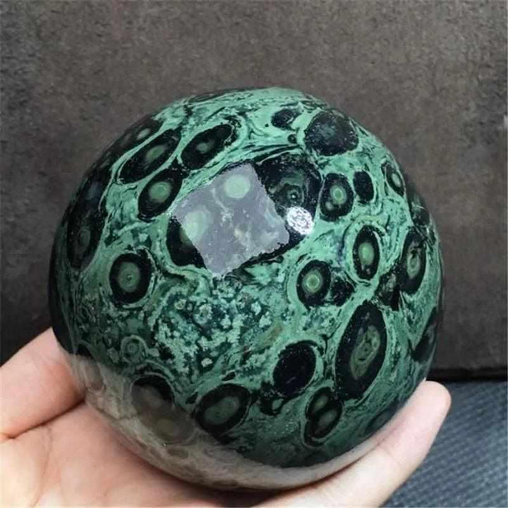 Polished Kambaba Jasper sphere featuring deep green and black stromatolite rings for grounding and heart chakra healing.