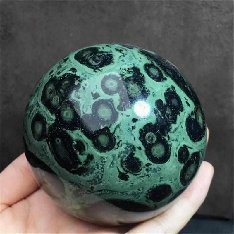 Polished Kambaba Jasper sphere featuring deep green and black stromatolite orbs for grounding and heart chakra healing.
