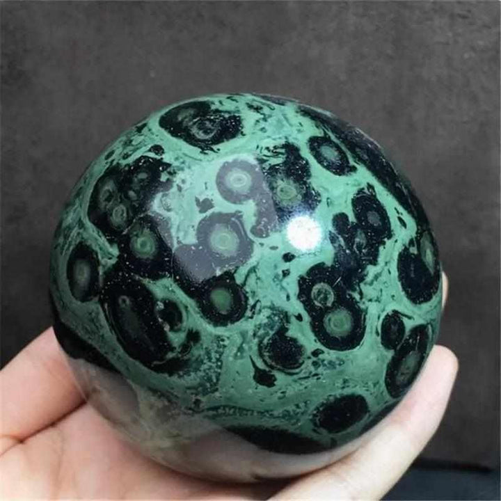 Polished Kambaba Jasper sphere featuring deep green and black stromatolite orbs for grounding and heart chakra healing.