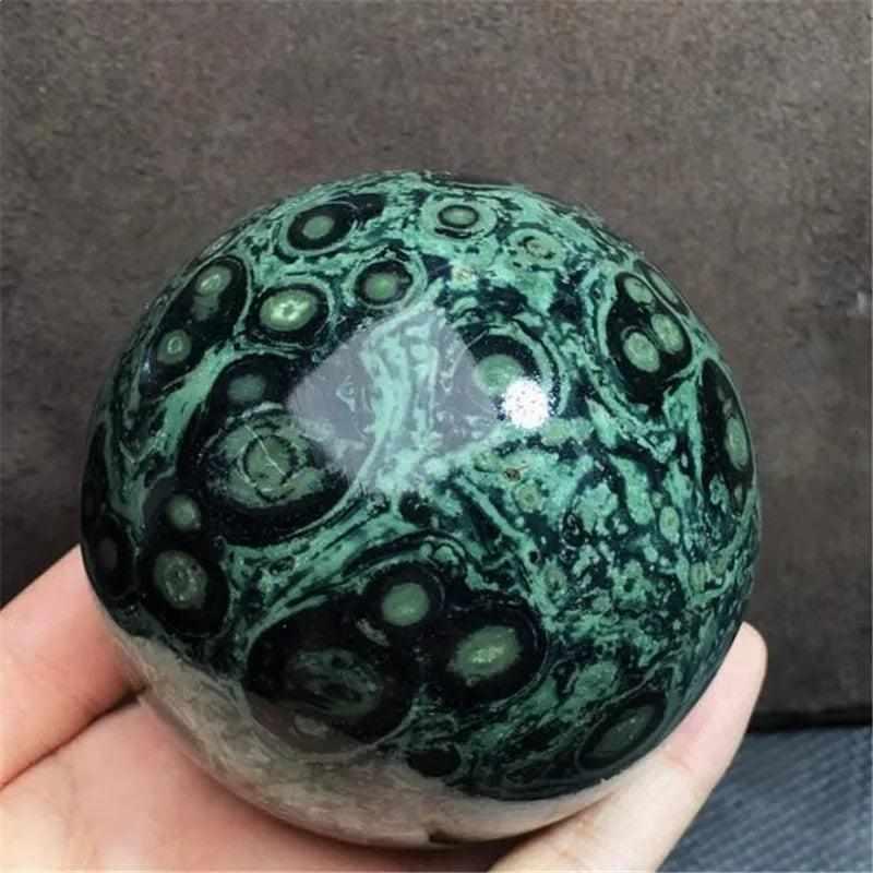 Polished Kambaba Jasper sphere featuring deep green and black stromatolite orbs for grounding and heart chakra healing.