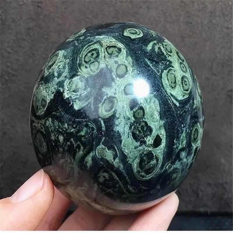 Polished Kambaba Jasper sphere featuring deep green and black stromatolite orbs for grounding and heart chakra healing.