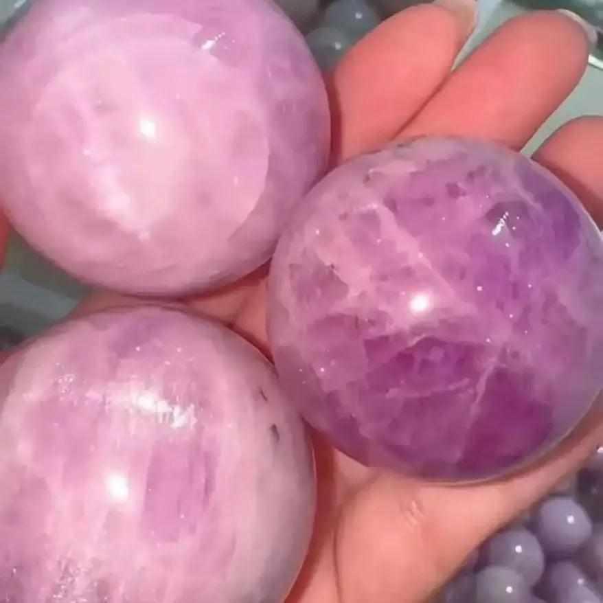 Polished pink and lilac Kunzite spheres held in hand, perfect for heart chakra healing and emotional calm.