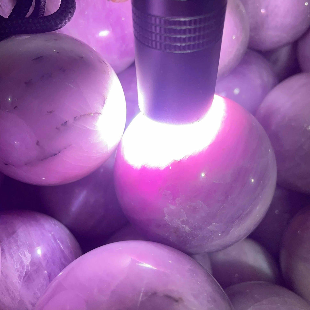 Polished pink and lilac Kunzite sphere glowing under light, perfect for heart chakra meditation and emotional calm.