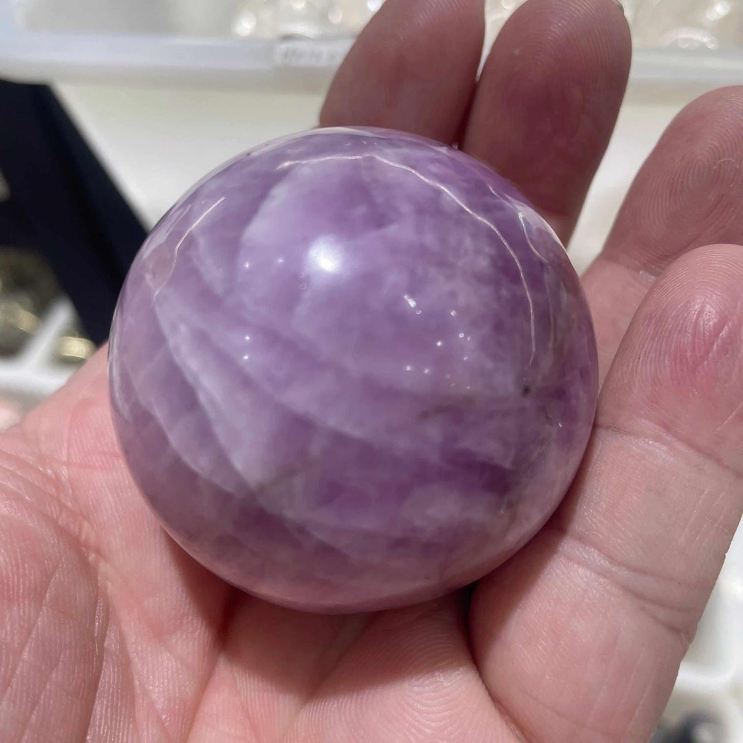 Polished natural kunzite sphere in soft pink and lilac, perfect for heart chakra meditation and emotional calm.