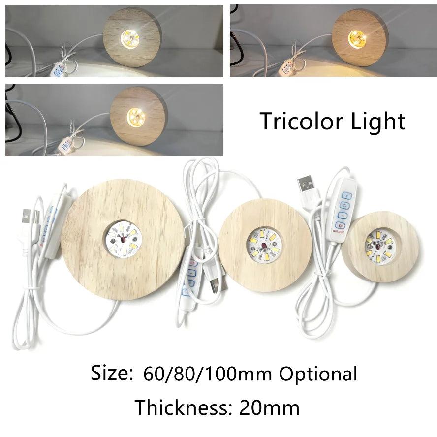 Three round wooden LED light bases with USB cables, showing white, warm, and tricolor light modes.