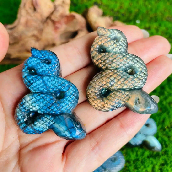 Two hand-carved Labradorite coiled snake figures, one vibrant blue, one golden, showcasing electric labradorescence.
