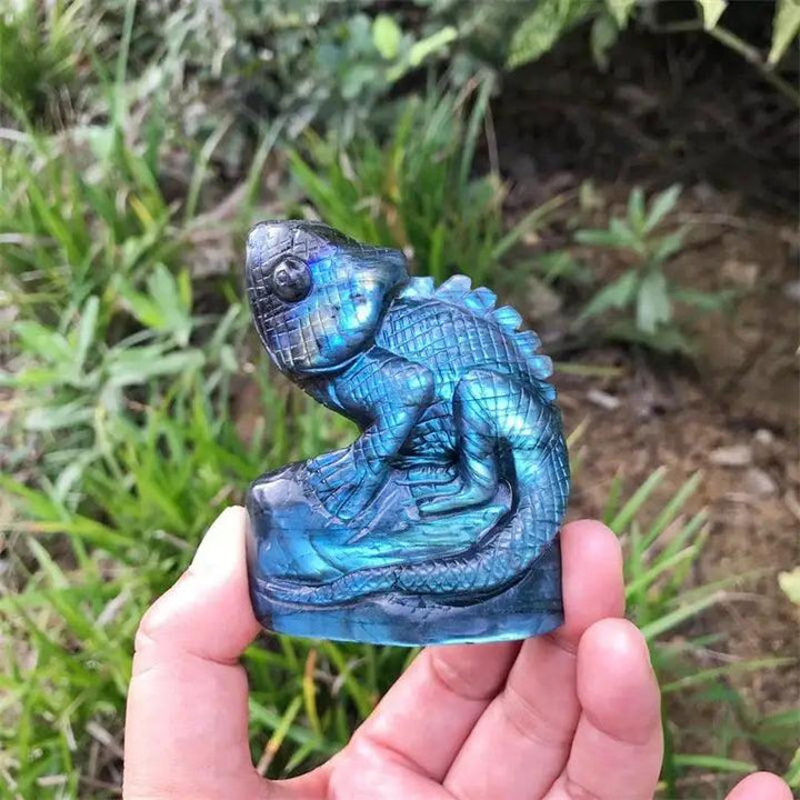 Iridescent blue-green Labradorite crystal carved lizard statue, 70mm, held in hand, showcasing labradorescence.