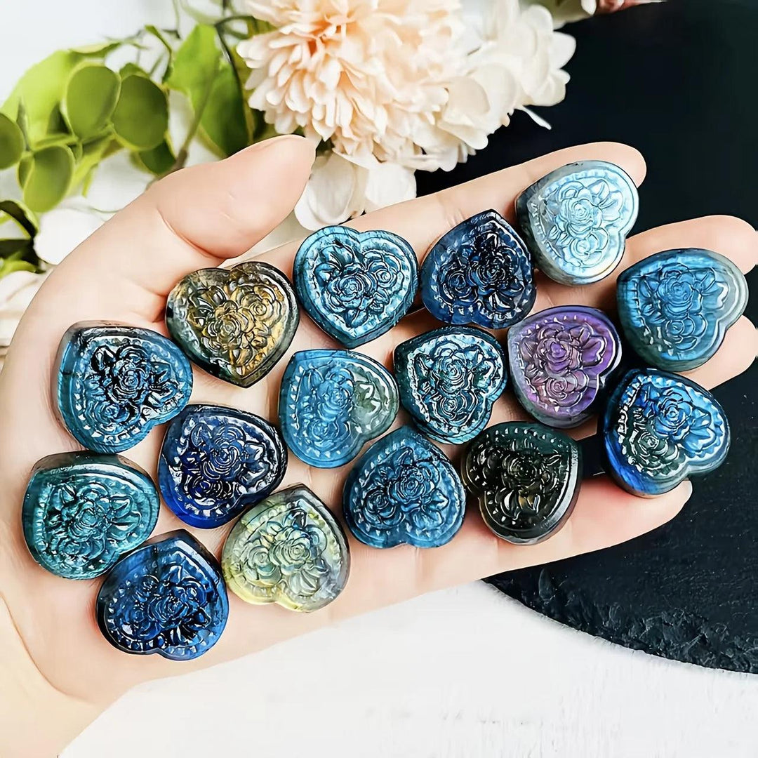 Handheld Labradorite Crystal Carved Love Heart pendants featuring iridescent blue, green, and gold floral engravings.