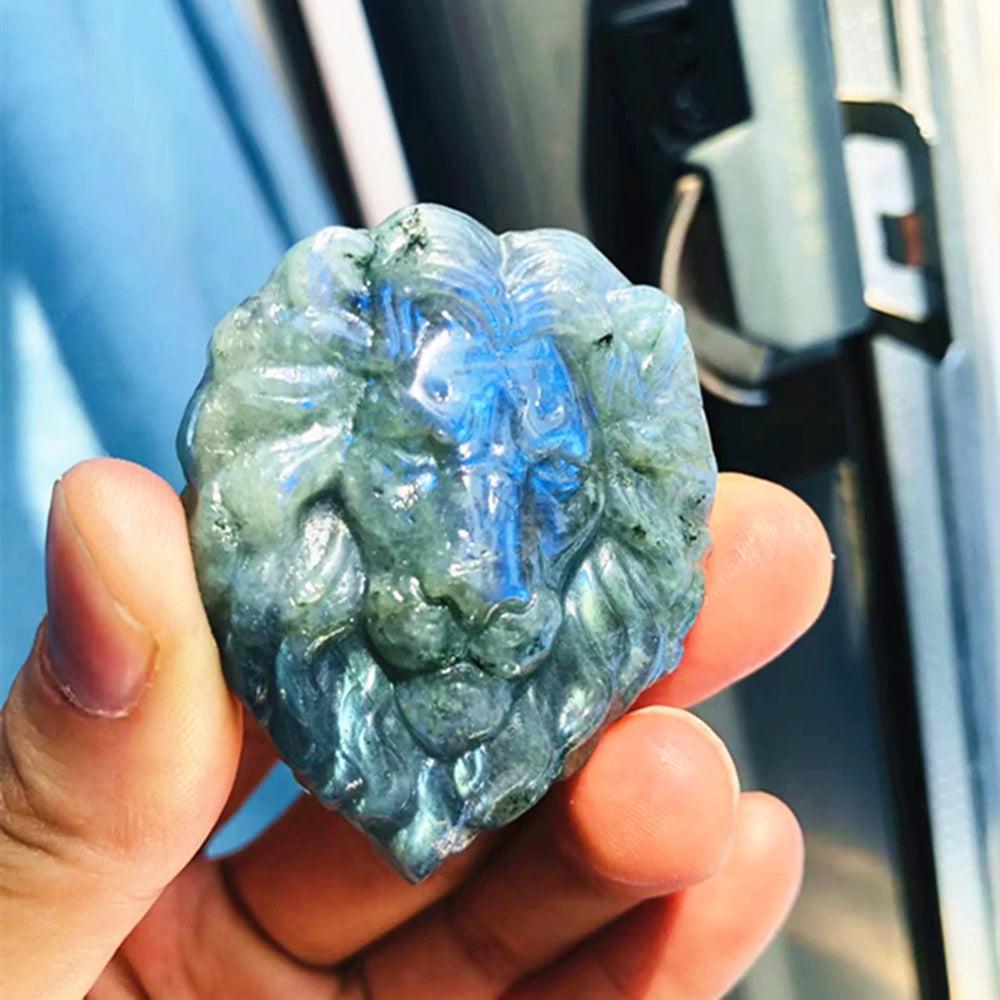 Labradorite Crystal Carved Polished Lion Head Carving with iridescent blue and green flash, held in hand.