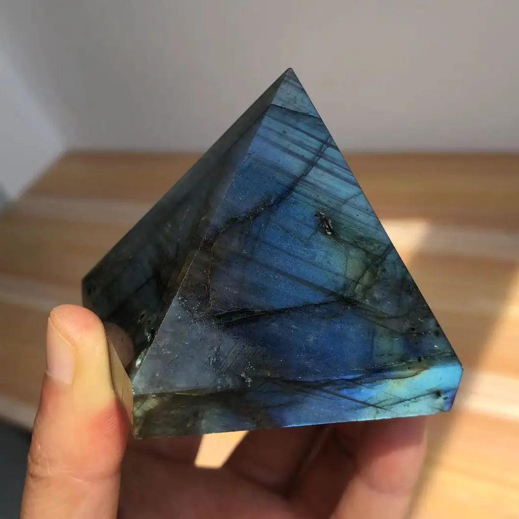Polished Labradorite crystal pyramid with iridescent blue and teal flashes, held in a hand.
