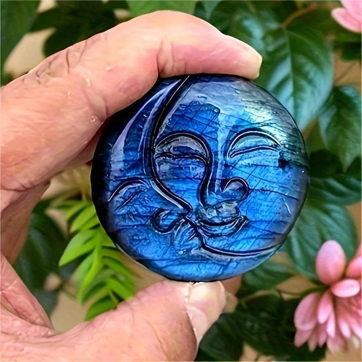 Hand holding a shimmering blue labradorite crystal moon and sun carving, radiating intuition and clarity.