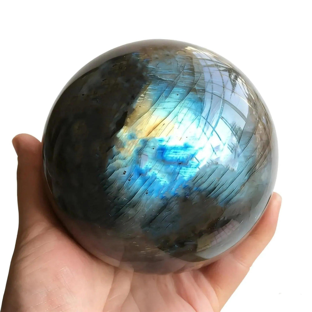 Hand holding a shimmering Labradorite crystal sphere, radiating blue and gold flashes for purpose & direction.