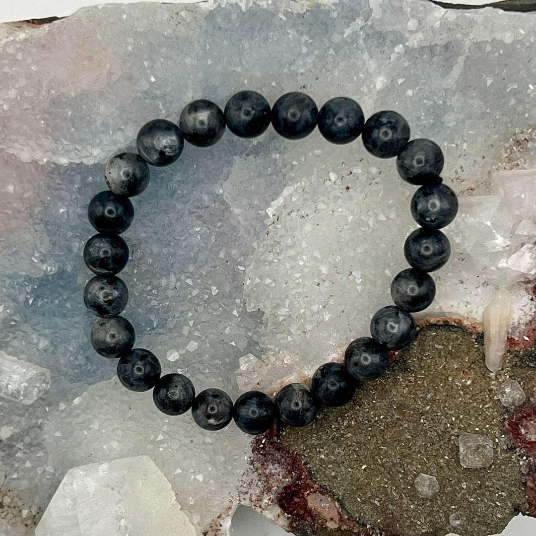 Luminous Labradorite Stretch Beaded Bracelet with dark gray beads, flashing blue and green, for protection and spiritual growth.