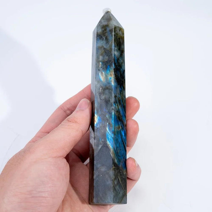 Hand holding a polished Labradorite Crystal Tower, showcasing vivid blue, gold, and green labradorescence for protection and growth.