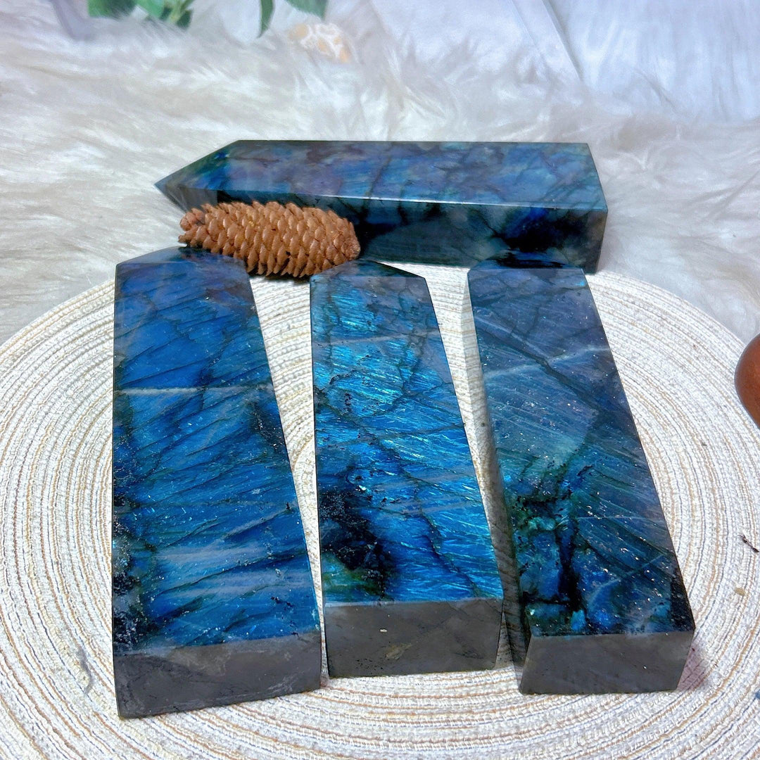 Four polished Labradorite crystal towers with vivid blue, teal, and violet labradorescence, one lying horizontally.