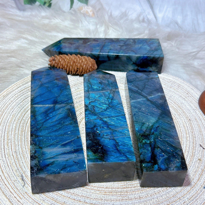 Four polished Labradorite crystal towers with vivid blue, teal, and violet labradorescence, one lying horizontally.