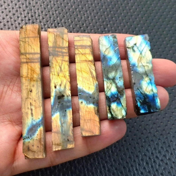 Raw labradorite crystal sticks with vivid blue and gold spectral flashes held in a hand for Third Eye Chakra healing.