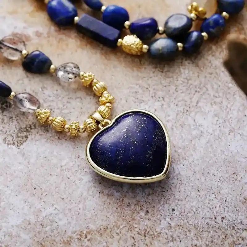Deep blue Lapis Lazuli heart pendant on a gold-beaded lariat necklace with clear quartz, promoting wisdom and clarity.