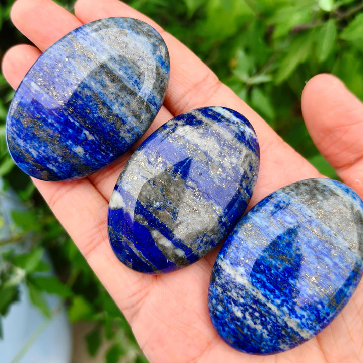 Three polished Lapis Lazuli Crystal Palm Stones with deep blue hues and golden pyrite flecks.