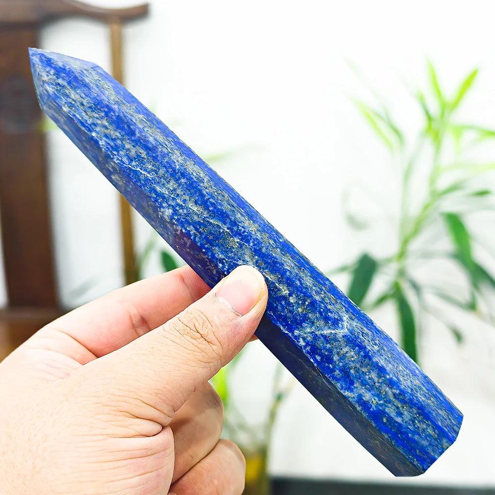 Hand holding a polished Lapis Lazuli Crystal Tower, deep midnight blue with gold pyrite flecks, for wisdom and truth.