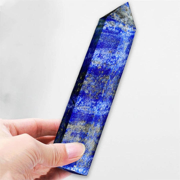 Hand holding a polished Lapis Lazuli Crystal Tower, deep midnight blue with gold pyrite and white calcite.