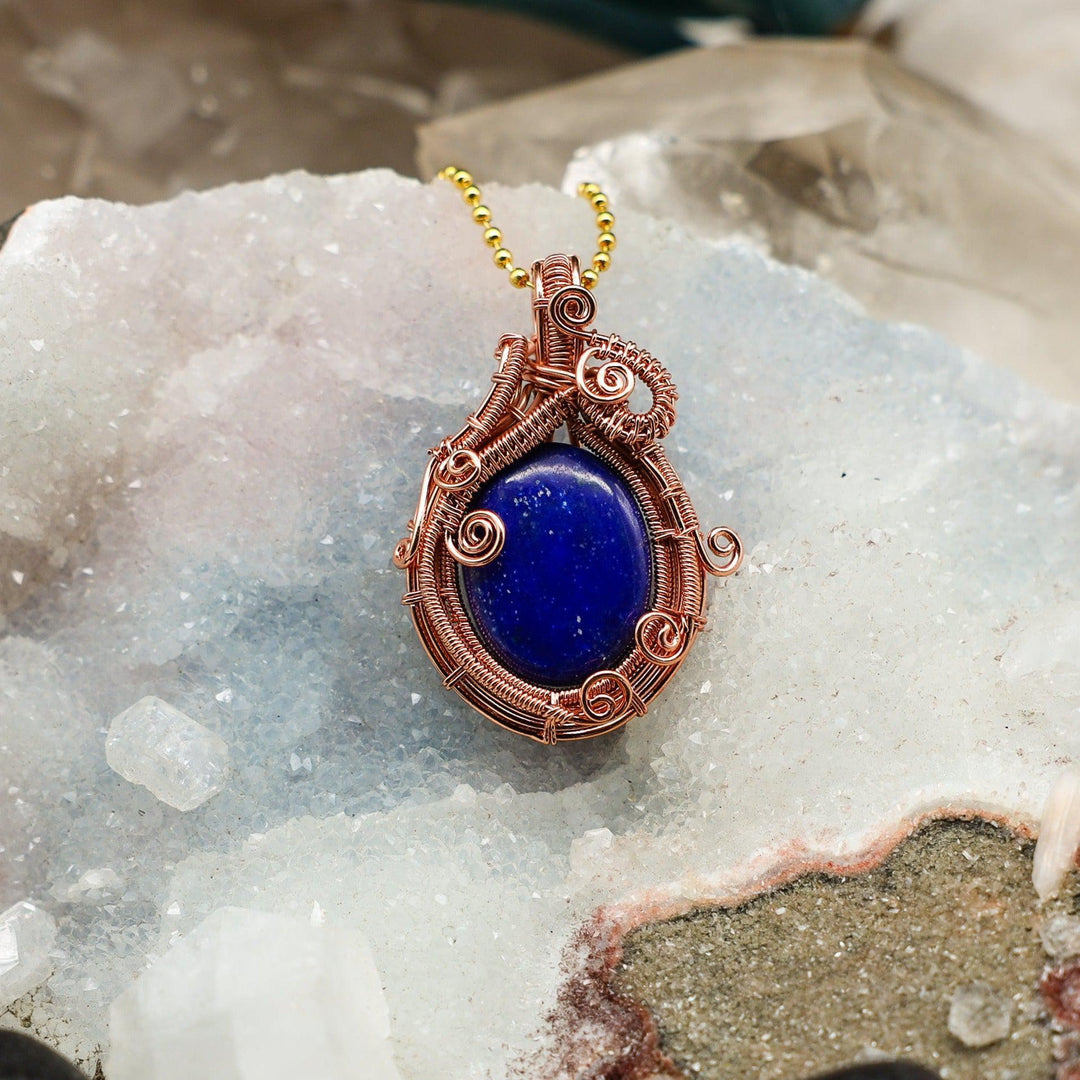 Lapis Lazuli Wire Wrap Pendant, 2.05" deep blue gemstone handcrafted in healing copper, on a crystal bed.