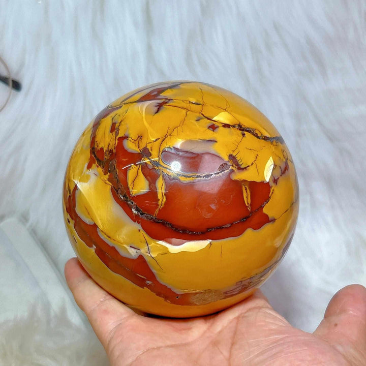 Large polished Mookaite sphere in vibrant red, yellow, and cream swirls for grounding and root chakra energy.