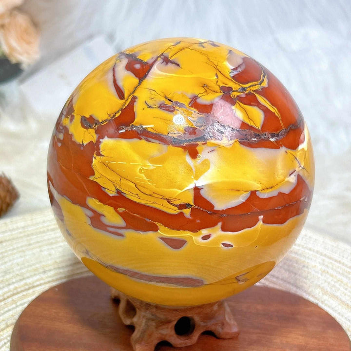 Large Mookaite sphere with stand, featuring vibrant red, yellow, and cream swirls for grounding and steady energy.
