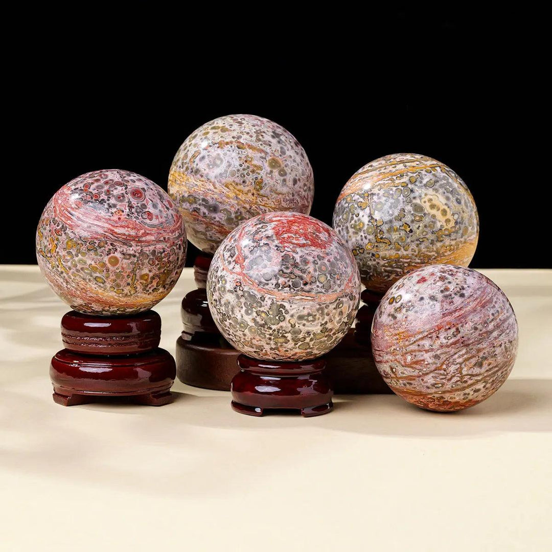 Polished Leopard Agate spheres featuring tan, brown, and black spots for grounding and Root Chakra energy.