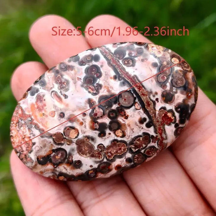 Leopard Skin Jasper Palm Stone: Polished, ergonomic crystal with spotted patterns in red, black, gold, and pink.