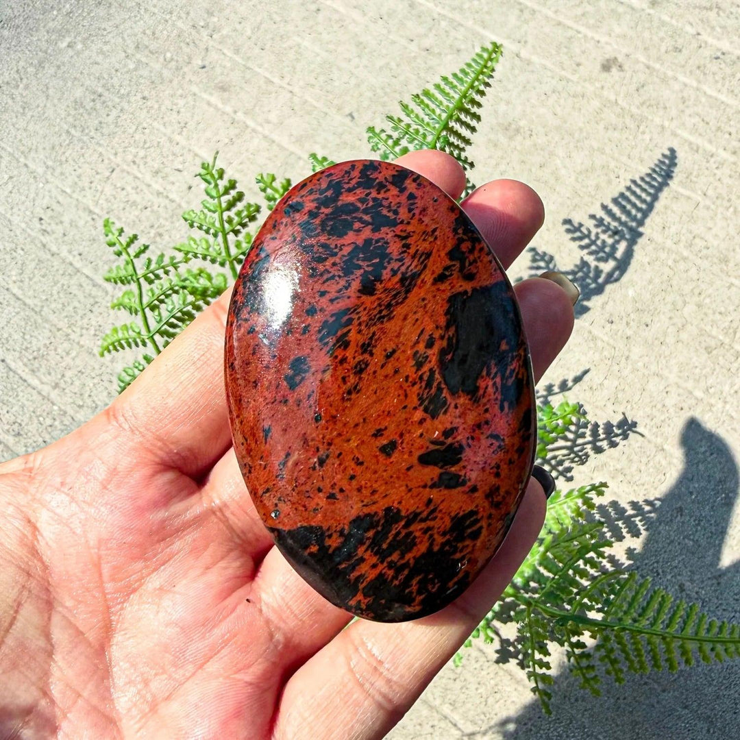 Polished Bohemian mahogany obsidian palm stone with striking red-brown and black veining for healing and home decor.