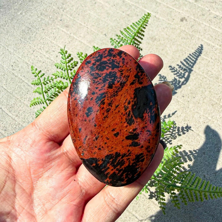 Polished Bohemian mahogany obsidian palm stone with striking red-brown and black veining for healing and home decor.