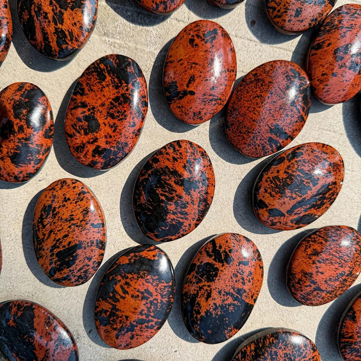 Polished mahogany obsidian palm stone with striking red-brown and black veining, perfect for home decor and crystal healing.