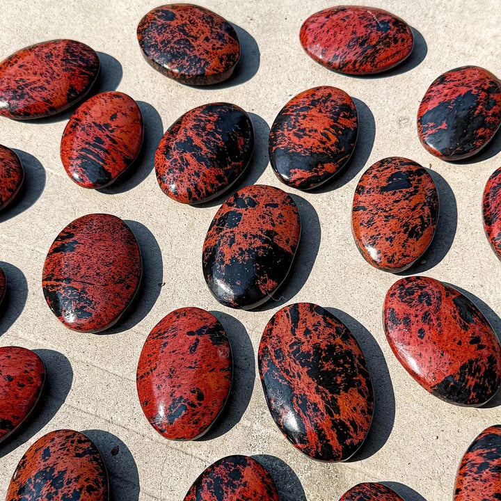 Polished natural Bohemian crystal palm stone with striking red-brown and black veining, perfect for decor or healing.