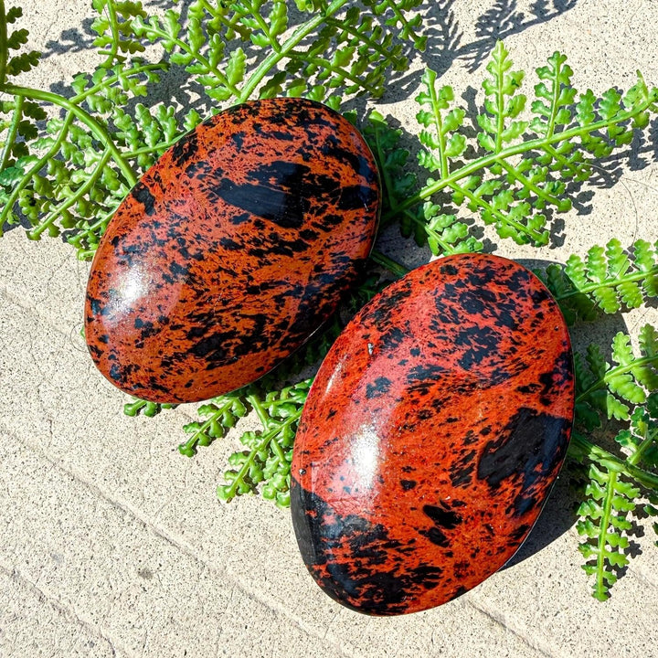 Polished mahogany obsidian palm stone with striking red-brown and black veining, perfect for healing and home decor.