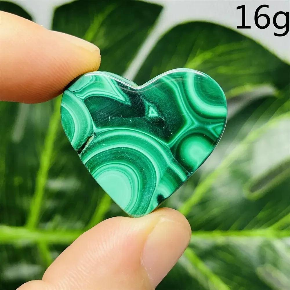 Polished Malachite Crystal Heart, showcasing deep forest green bands, held between fingers. Powerful transformation stone.