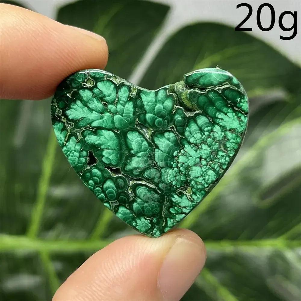 Polished Malachite Crystal Heart, deep forest green with mesmerizing banded patterns, held between fingers.