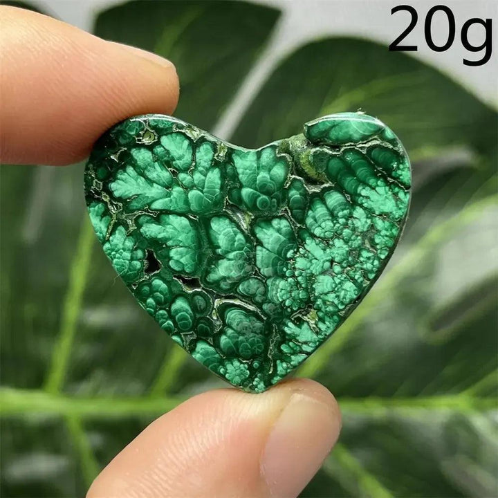 Polished Malachite Crystal Heart, deep forest green with mesmerizing banded patterns, held between fingers.
