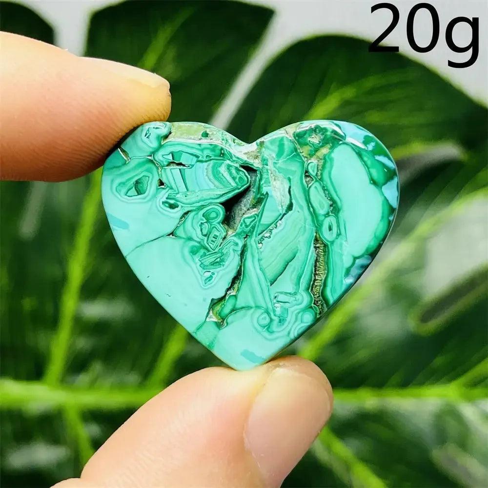 Handcrafted Malachite Crystal Heart, a powerful transformation stone with deep forest green swirls, held between fingers.