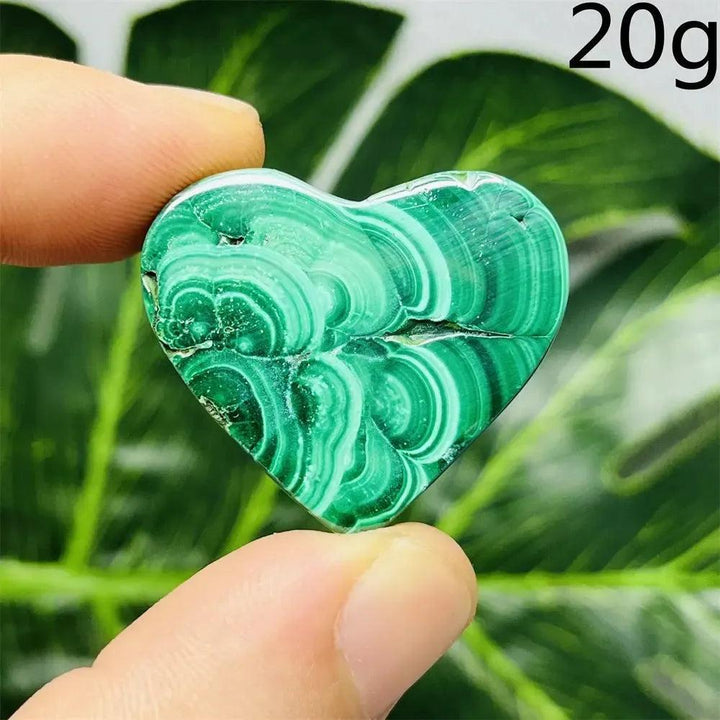 Malachite Crystal Heart: Polished deep forest green heart with mesmerizing banded patterns, held by fingers.