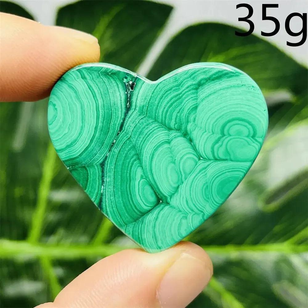 Malachite Crystal Heart: Polished deep forest green heart with mesmerizing banded patterns, held by fingers.