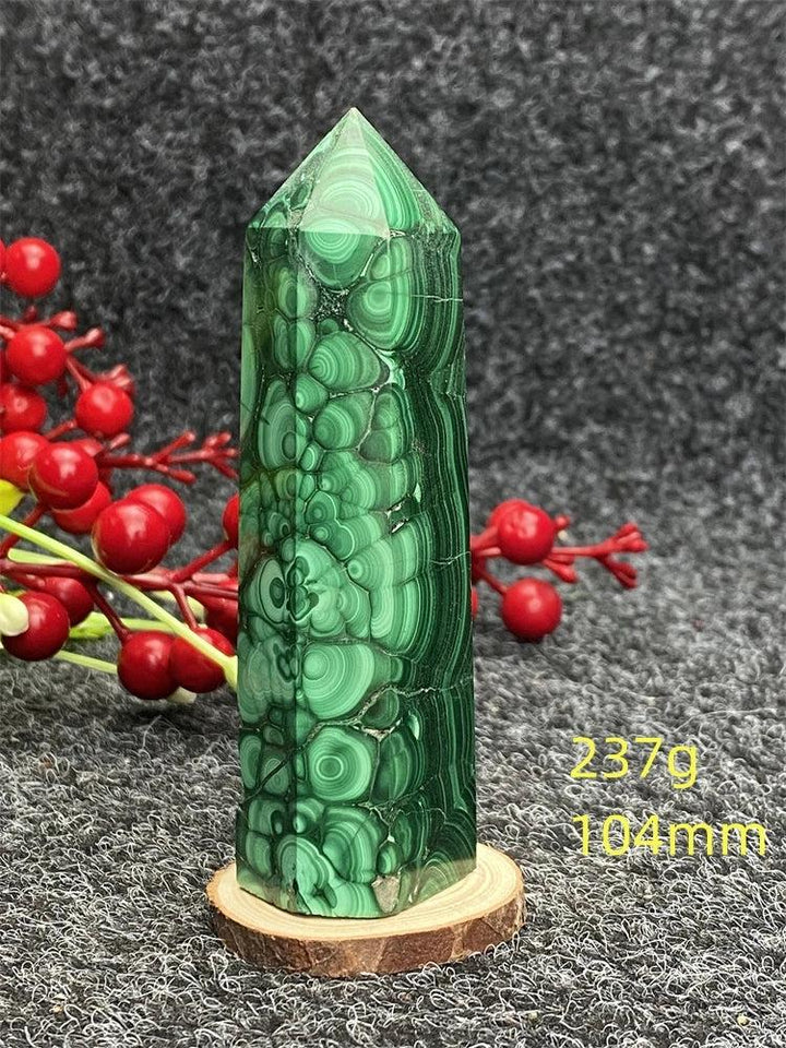 Polished malachite hexagonal obelisk tower with vibrant green banded patterns for healing and transformation.
