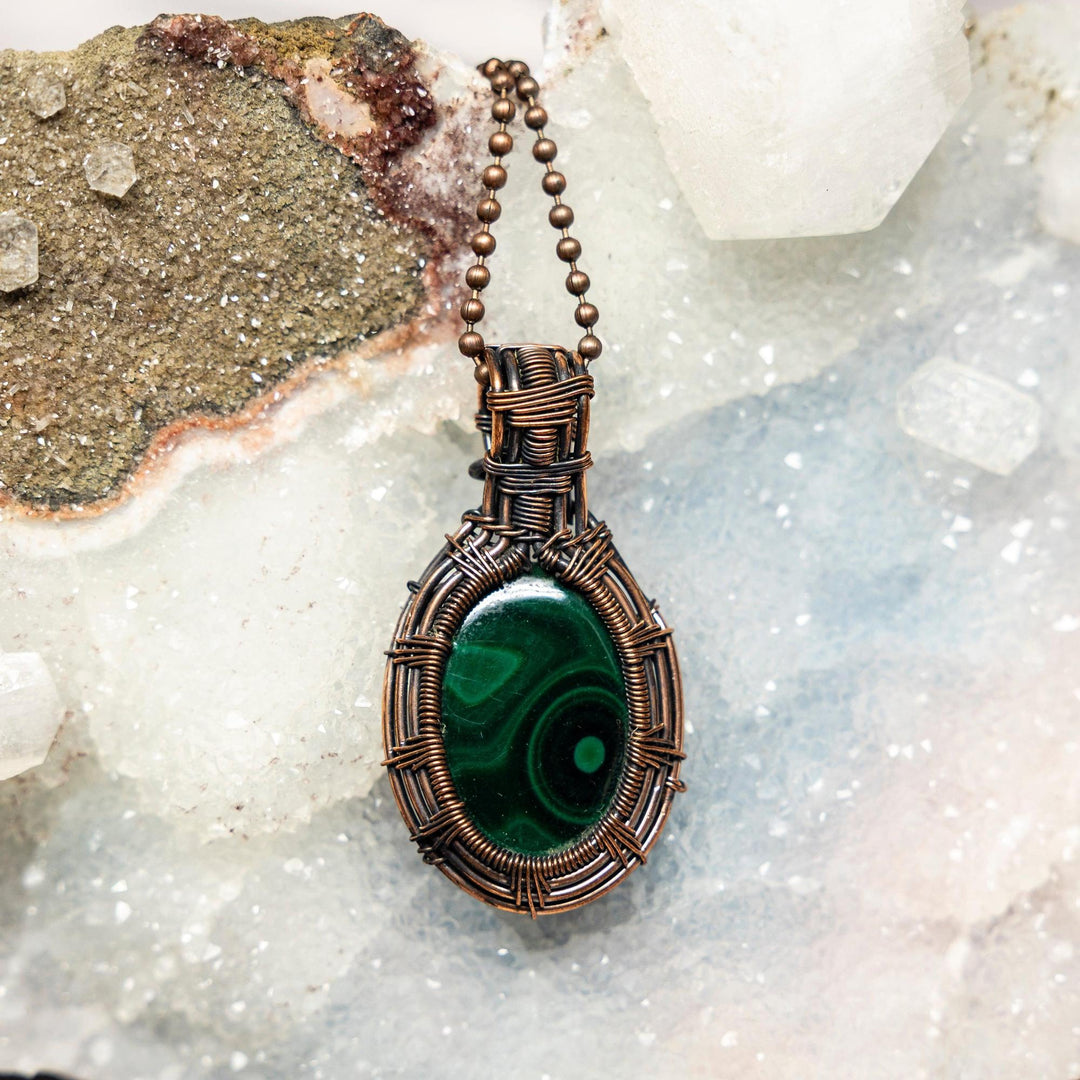 Malachite Oval Wire Wrap Pendant: Deep green malachite stone in handcrafted copper wire, promoting heart-centered transformation.