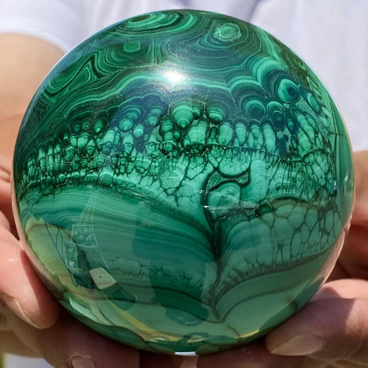 Polished Malachite Crystal Sphere featuring vibrant, swirling forest green bands for heart chakra healing and energy.
